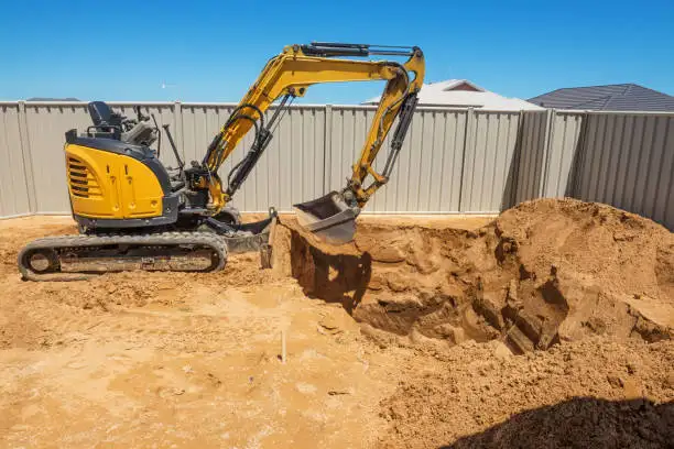 Excavator digging out a building site behind a fence
