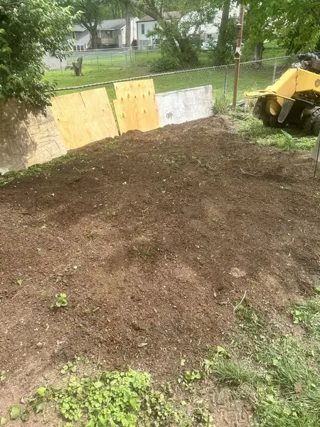 Cleared dirt area beside plywood boards after stump grinding