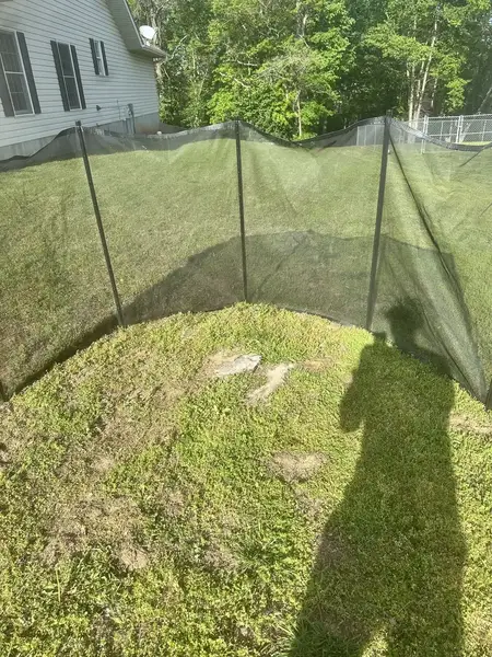 Safety screen set up around stumps on a sloped lawn