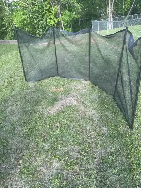 Safety screen on a lawn near a chain-link fence before grinding
