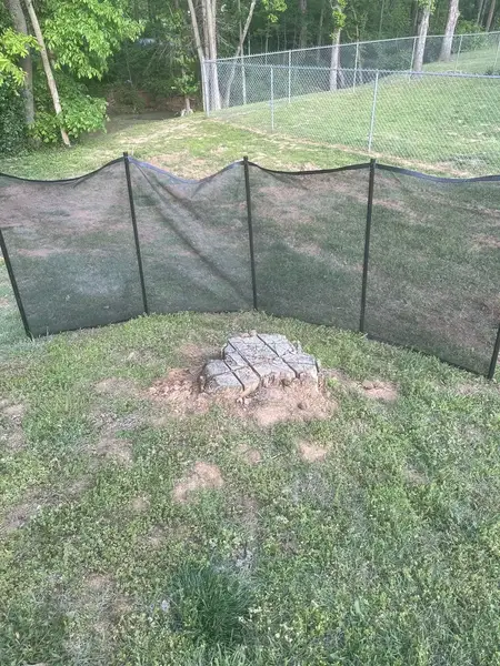 Stump behind a safety screen near a chain-link fence