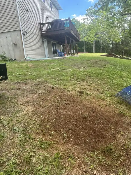 Ground-out area in a backyard behind a house with a deck