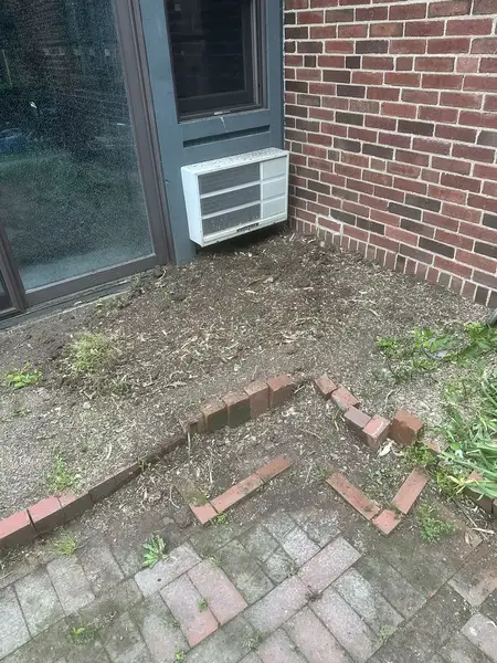 Garden bed by a brick wall after stump removal