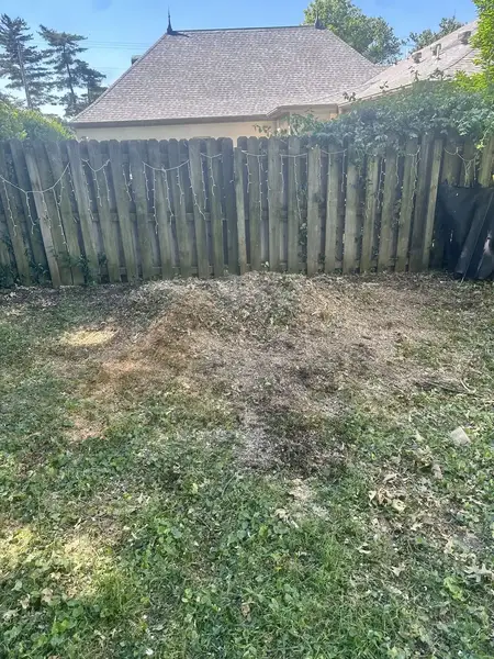 Ground-out area along a wooden fence after stump grinding