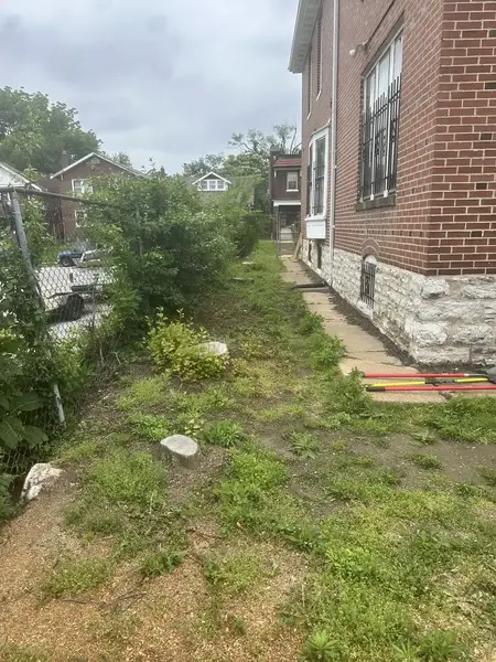 Narrow side yard between brick houses with small stumps