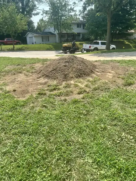 Wood chip mound by the street with the grinder behind it